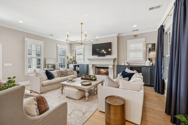 living room featuring ornamental molding, a chandelier, and light wood-type flooring