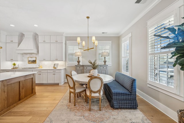 dining space featuring a chandelier, crown molding, and light hardwood / wood-style flooring