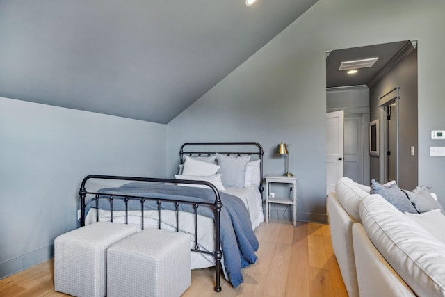 bedroom featuring ornamental molding, light hardwood / wood-style flooring, and lofted ceiling