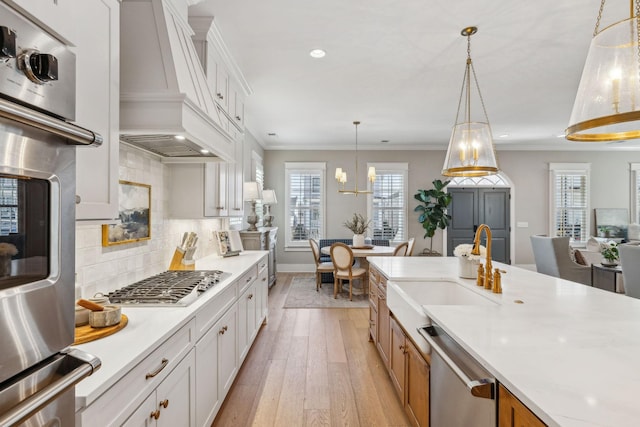 kitchen featuring custom exhaust hood, white cabinets, appliances with stainless steel finishes, and pendant lighting