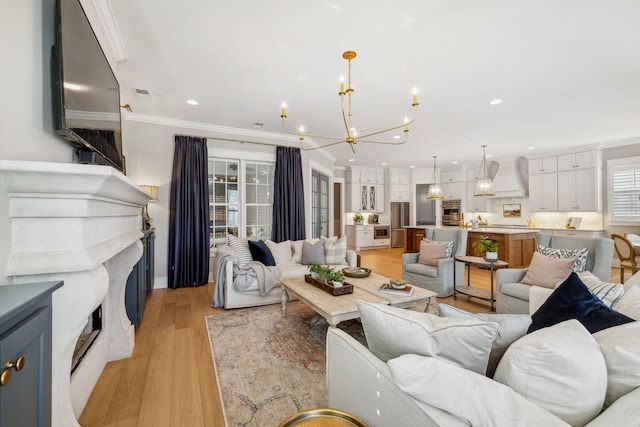 living room with ornamental molding, light hardwood / wood-style floors, and a notable chandelier