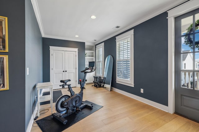 workout room featuring ornamental molding and light wood-type flooring