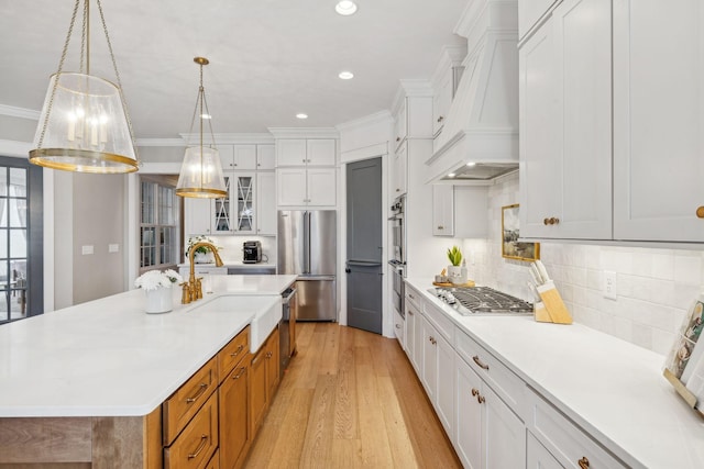 kitchen with appliances with stainless steel finishes, white cabinets, and an island with sink