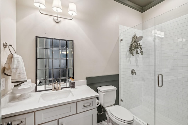 bathroom with toilet, vanity, a shower with door, and ornamental molding