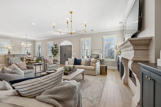 living room featuring light wood-type flooring, a premium fireplace, an inviting chandelier, and ornamental molding