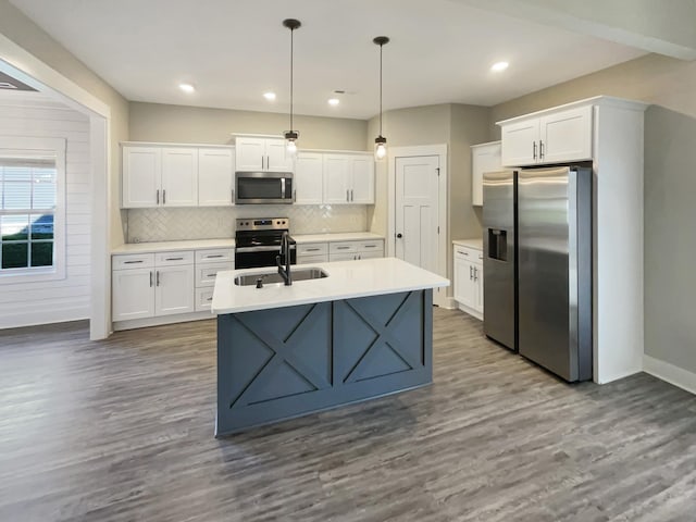 kitchen featuring hardwood / wood-style floors, appliances with stainless steel finishes, white cabinetry, sink, and hanging light fixtures