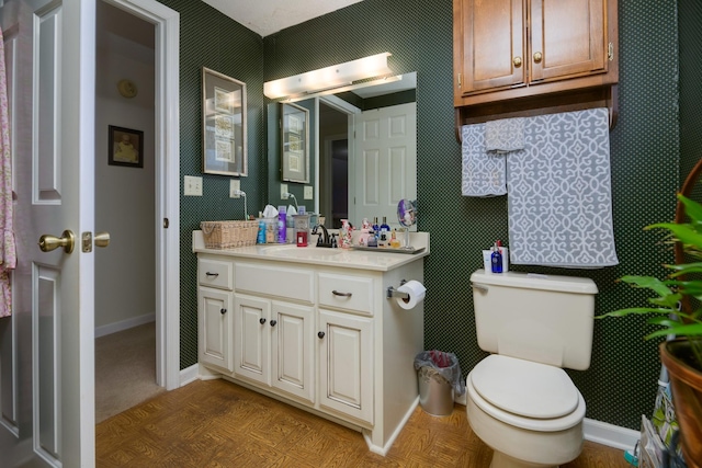 bathroom with vanity, toilet, and parquet flooring