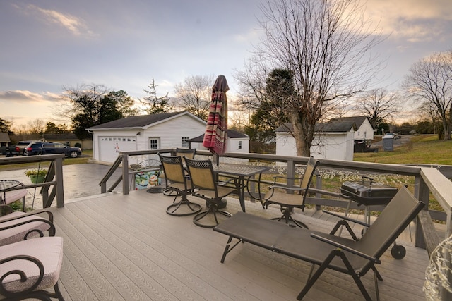 deck at dusk with a garage and an outbuilding