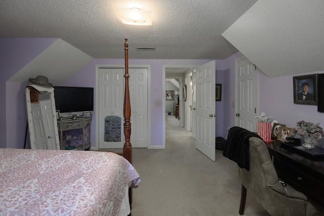 bedroom with a closet, vaulted ceiling, a textured ceiling, and light carpet