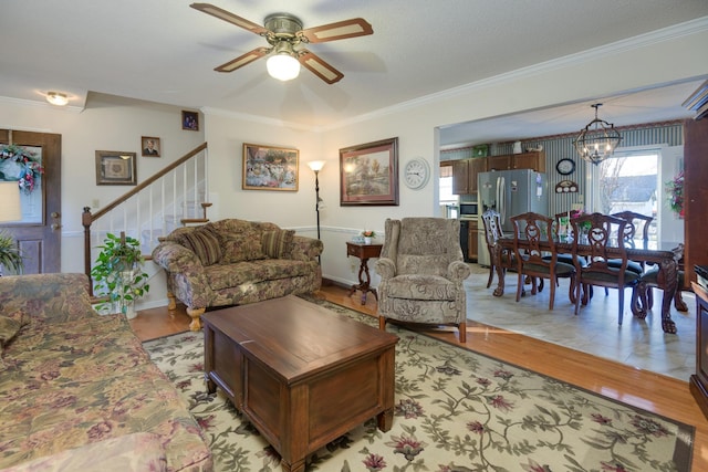 living room with ceiling fan with notable chandelier, a textured ceiling, crown molding, and light wood-type flooring