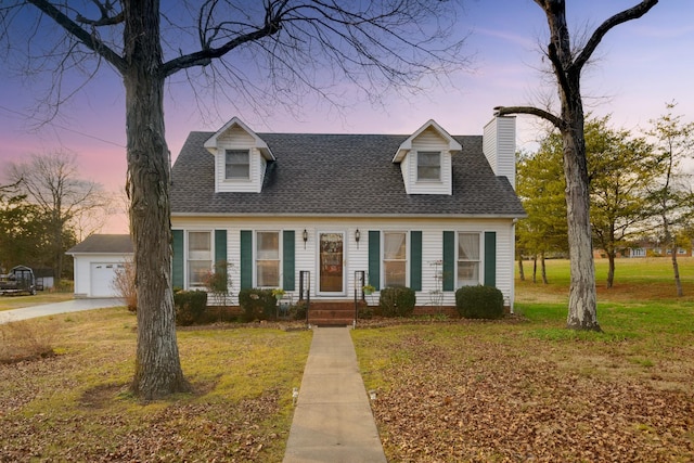 cape cod house featuring a lawn and a garage