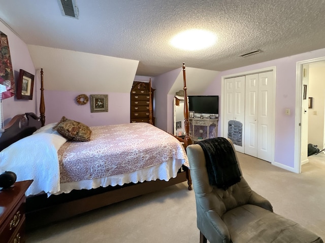 carpeted bedroom with a textured ceiling, a closet, and vaulted ceiling