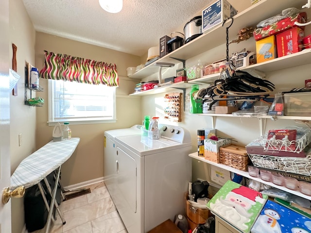 clothes washing area with washer and dryer and a textured ceiling