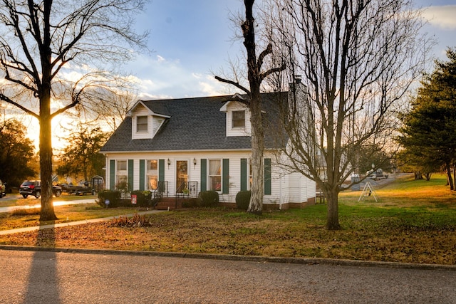 cape cod house featuring a lawn