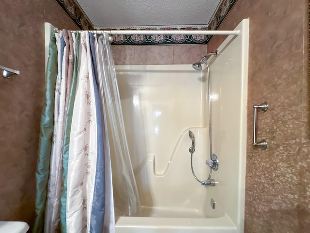 bathroom with a textured ceiling and shower / tub combo with curtain