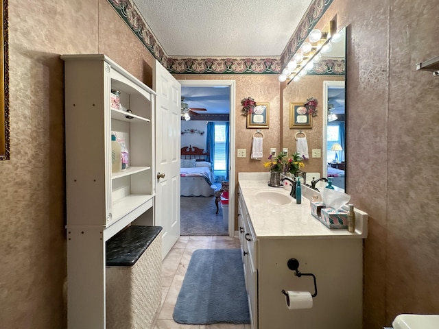 bathroom with a textured ceiling, tile patterned flooring, ceiling fan, and vanity