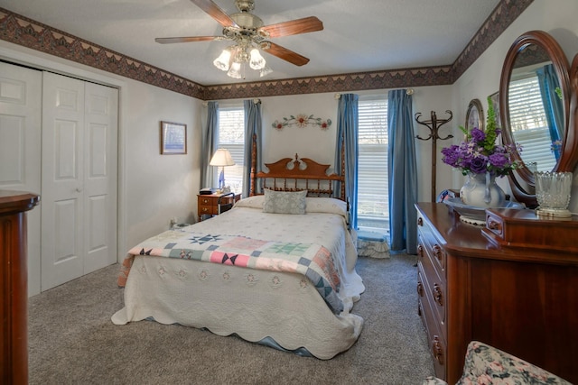 carpeted bedroom featuring ceiling fan, multiple windows, a closet, and a textured ceiling