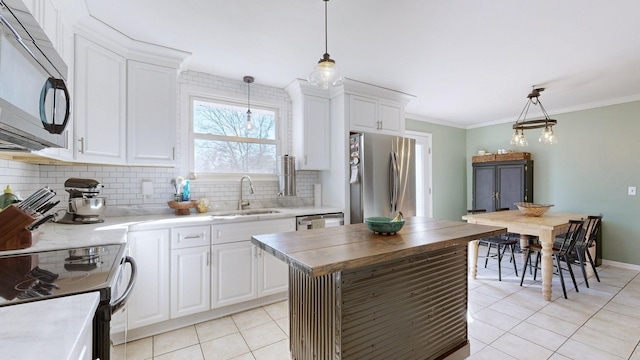 kitchen featuring appliances with stainless steel finishes, white cabinetry, sink, hanging light fixtures, and light tile patterned floors