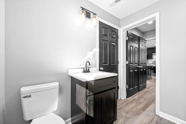 bathroom with toilet, wood-type flooring, and vanity