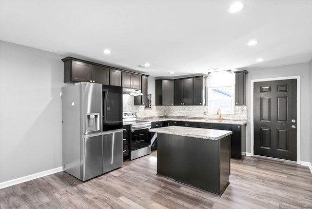 kitchen featuring light hardwood / wood-style floors, stainless steel appliances, light stone countertops, a kitchen island, and sink