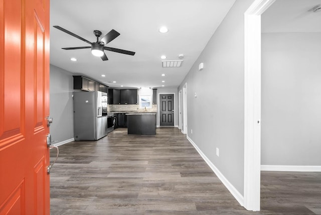 kitchen featuring stainless steel fridge, ceiling fan, decorative backsplash, dark hardwood / wood-style floors, and a kitchen island