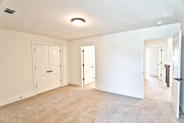 unfurnished bedroom with a closet and light carpet