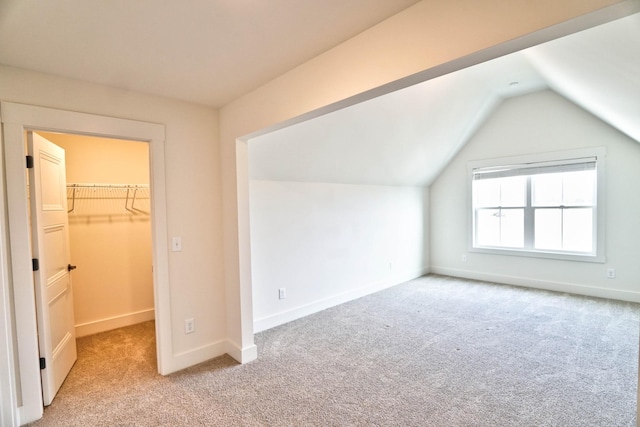 bonus room with lofted ceiling and light colored carpet