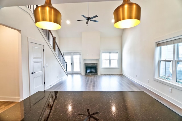 unfurnished living room with high vaulted ceiling, a wealth of natural light, and dark hardwood / wood-style flooring