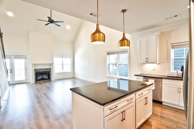 kitchen with backsplash, stainless steel dishwasher, light hardwood / wood-style flooring, hanging light fixtures, and white cabinets