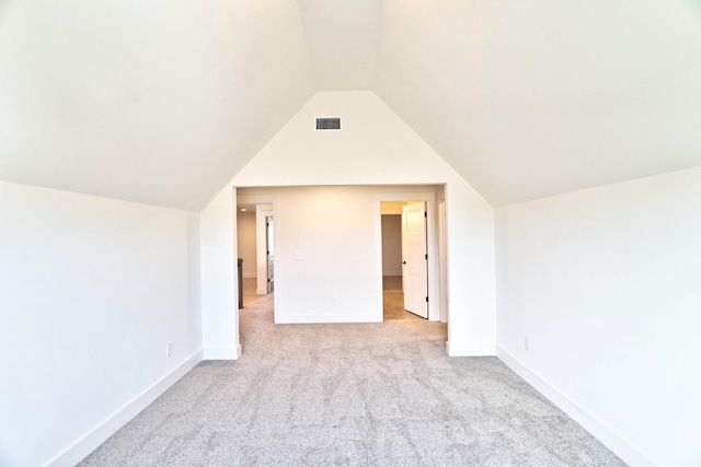 additional living space featuring light carpet and vaulted ceiling