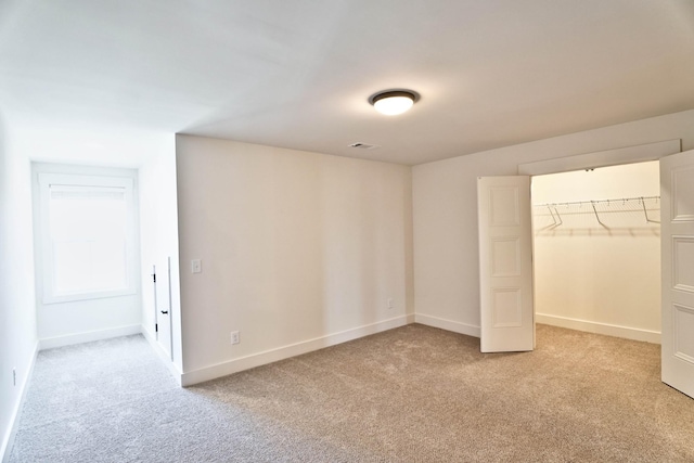 unfurnished bedroom featuring light colored carpet, a closet, and a walk in closet