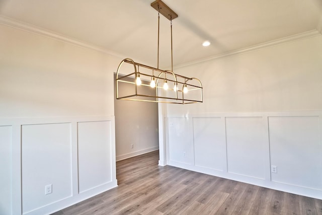 unfurnished dining area featuring wood-type flooring and crown molding