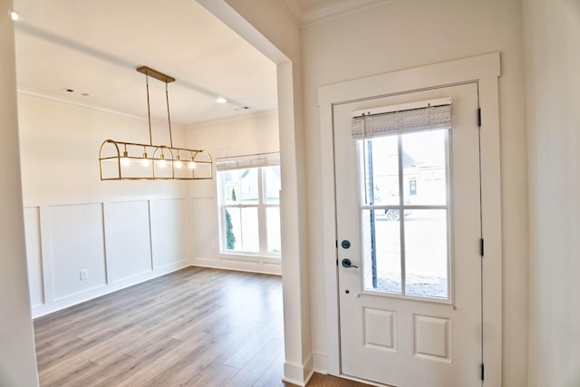 entryway with a healthy amount of sunlight, light wood-type flooring, and crown molding