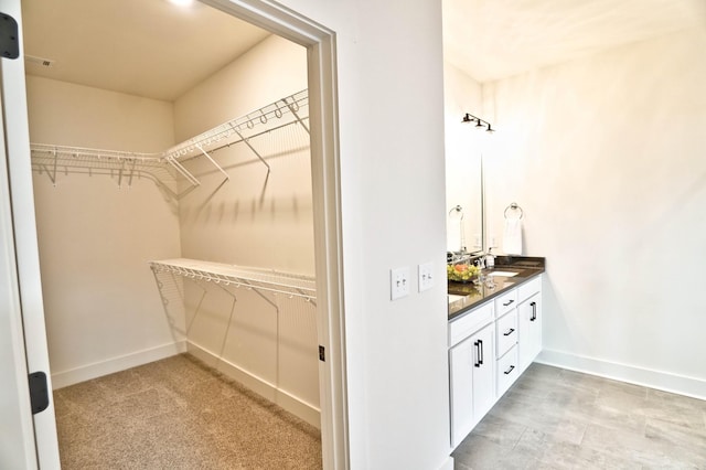 walk in closet with light colored carpet and sink