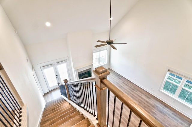 stairway featuring high vaulted ceiling, plenty of natural light, and hardwood / wood-style floors