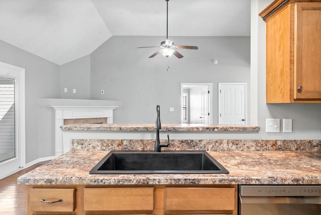 kitchen featuring dishwasher, lofted ceiling, sink, ceiling fan, and a tiled fireplace