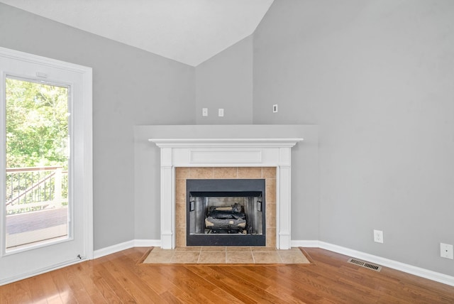 unfurnished living room with hardwood / wood-style flooring, vaulted ceiling, and a fireplace