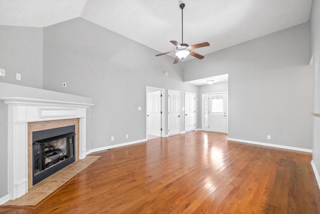 unfurnished living room with light wood-type flooring, ceiling fan, a fireplace, and high vaulted ceiling