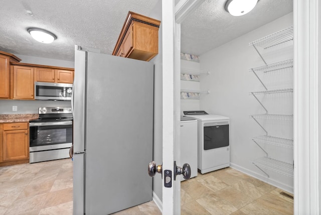 clothes washing area with washer and clothes dryer and a textured ceiling