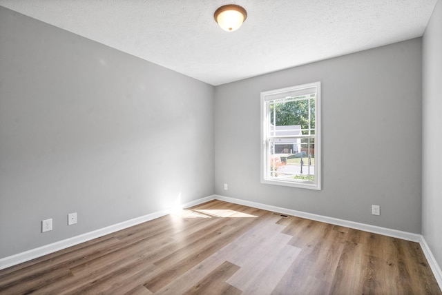 spare room featuring a textured ceiling and wood-type flooring