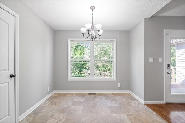 unfurnished dining area featuring a chandelier and a textured ceiling