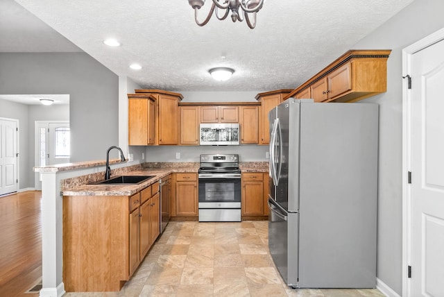 kitchen featuring sink, a textured ceiling, appliances with stainless steel finishes, and kitchen peninsula