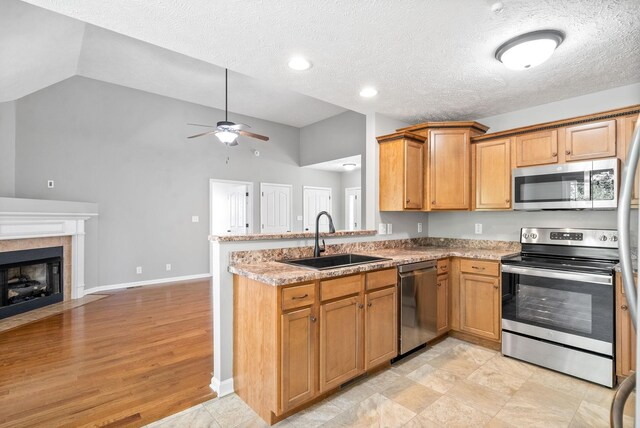 kitchen with sink, a textured ceiling, kitchen peninsula, and stainless steel appliances