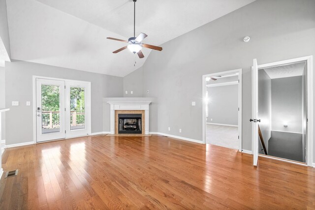 unfurnished living room with ceiling fan, a fireplace, wood-type flooring, and high vaulted ceiling