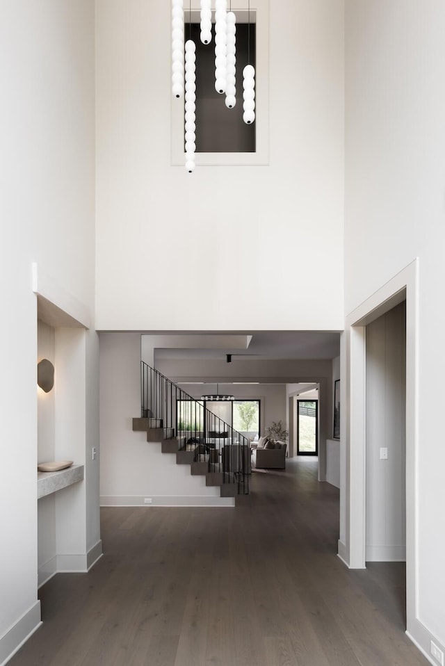 stairway featuring a high ceiling, wood-type flooring, and an inviting chandelier