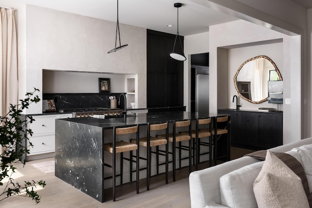 bar with backsplash, sink, white cabinetry, hanging light fixtures, and light wood-type flooring