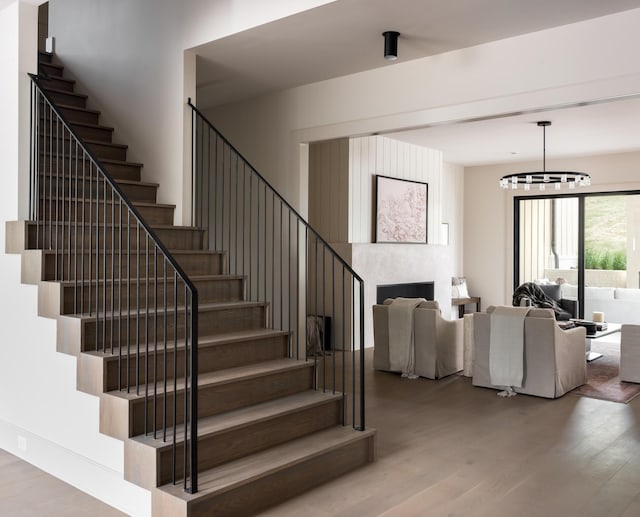 stairs featuring hardwood / wood-style flooring and a notable chandelier