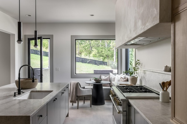 kitchen featuring premium range hood, high end stainless steel range, decorative light fixtures, light hardwood / wood-style flooring, and sink