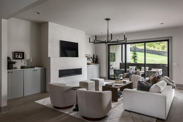 living room featuring wood-type flooring, a fireplace, and an inviting chandelier