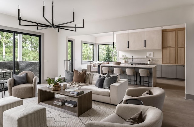 living room with a wealth of natural light, light hardwood / wood-style floors, and a notable chandelier